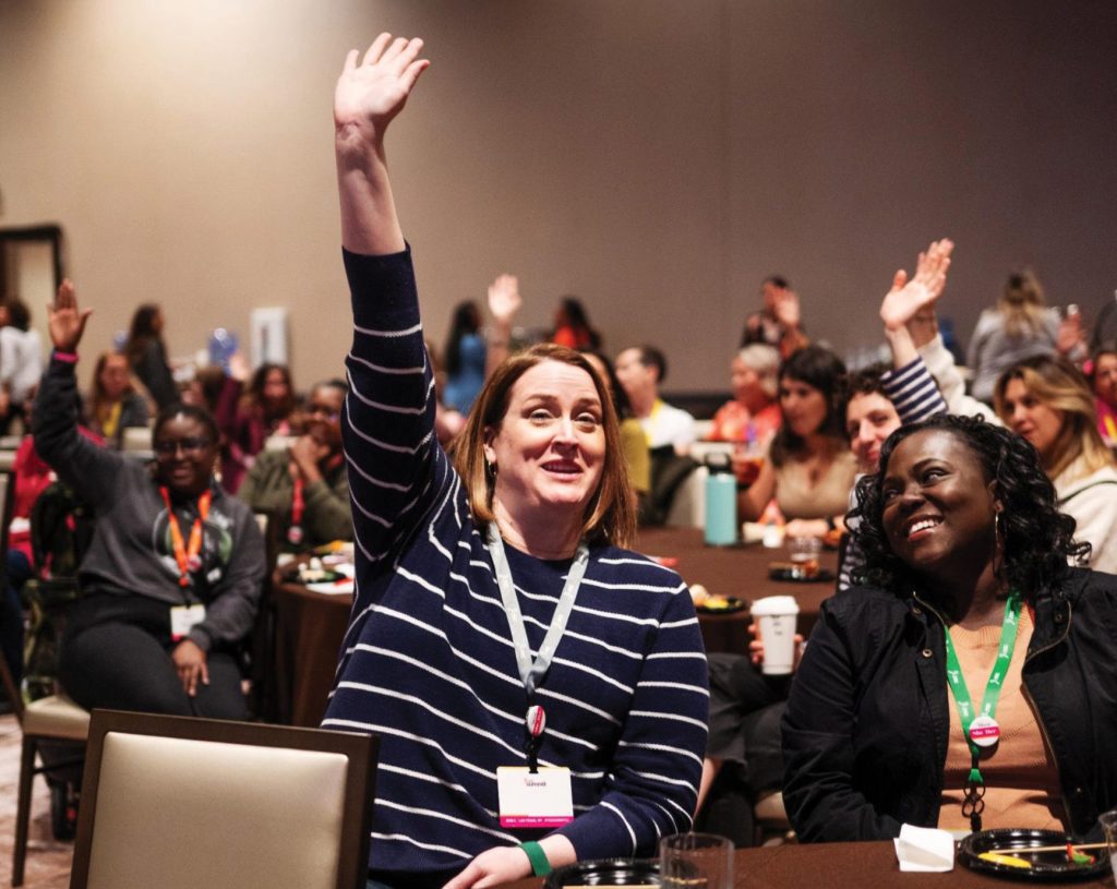 one woman raising hand and a woman next to her smiling